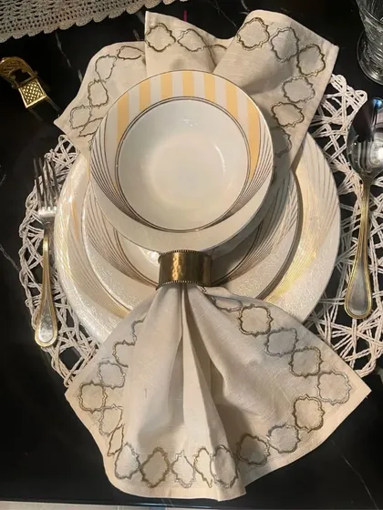 An example of an elegant place setting on a white woven placemat. The intricate pattern of the mat provides a beautiful textural contrast to the smooth, dark marble tabletop and crisp white dinnerware.