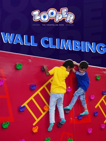 Two young climbers race to the top of our red wall climbing section, which features fun ladder-like holds for an easier ascent.