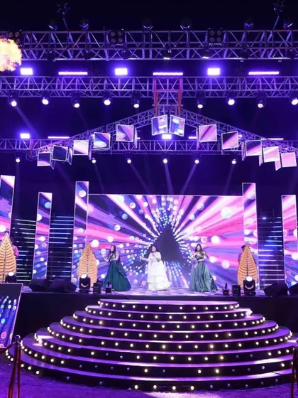 A full view of a spectacular Sangeet stage, complete with multi-level platforms, intricate lighting design, and professional dancers, ready for a night of stunning performances.