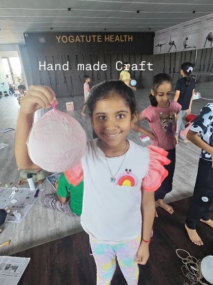 A young girl proudly shows off a handmade craft from our summer camp. These activities are designed to build confidence and a sense of accomplishment.