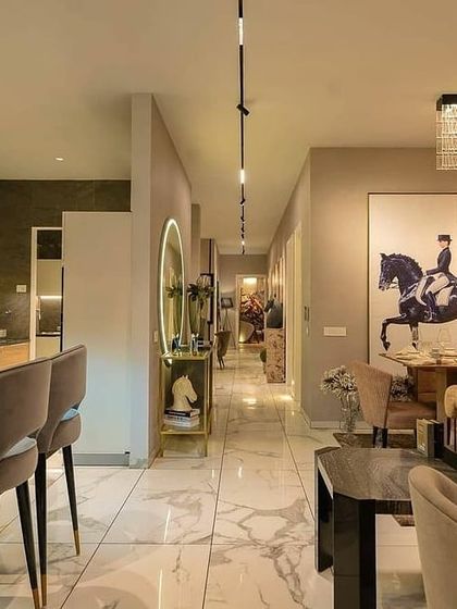 This long perspective shows how lighting creates a cohesive flow through the apartment. The continuous track lighting on the ceiling draws the eye from the bar and living area down the hall, connecting the different zones of the open-plan space.