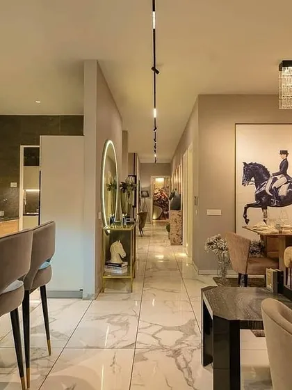 This long perspective shows how lighting creates a cohesive flow through the apartment. The continuous track lighting on the ceiling draws the eye from the bar and living area down the hall, connecting the different zones of the open-plan space.