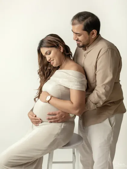 The couple stands together, both gently holding the baby bump. This pose beautifully symbolizes their shared role in nurturing and protecting their growing family.