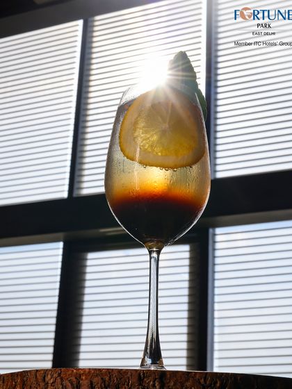 A sun-kissed cocktail at Neptune. The light streaming through the window creates a beautiful starburst effect, highlighting the drink's rich colors.