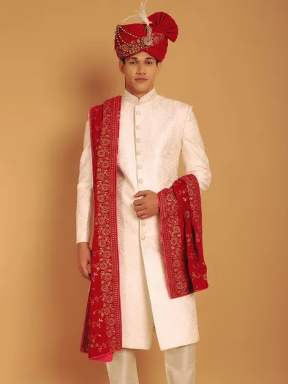 For a classic and powerful groom's look, I pair an ivory self-embroidered sherwani with a rich, red velvet stole. This combination of colors and textures creates a timeless and royal aesthetic, perfect for a grand wedding ceremony.