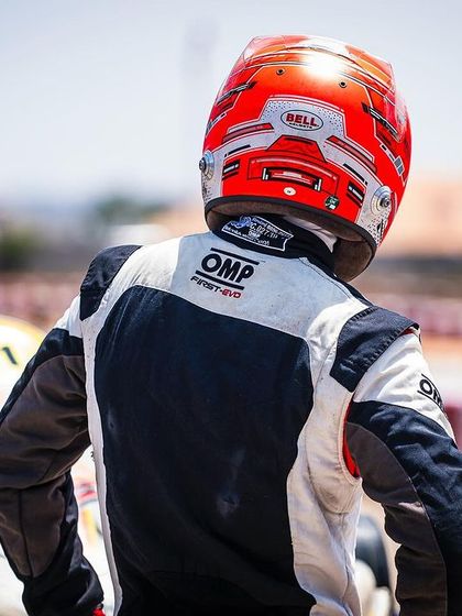 A driver stands ready by his kart, a picture of focus and determination before the final round of the Meritus Cup.