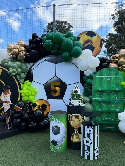 A close-up of the football party's dessert area, with a themed cake, trophy props, and custom-designed pedestals.