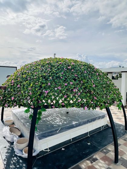 Another view of the custom-built green canopy. The structure provides dappled shade, mimicking the effect of a natural flowering vine, perfect for a rooftop lounge area.