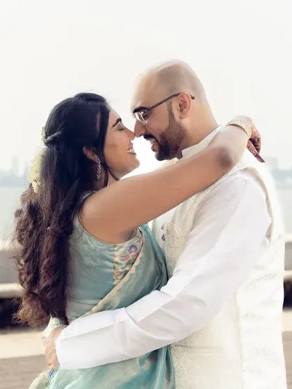 An intimate embrace by the sea, with the Mumbai skyline faintly visible. This photo captures the essence of urban romance.