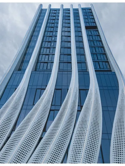 The clean, modern lines of the facade are visible in this daytime shot, showing the contrast between the solid panels and the glass curtain wall.