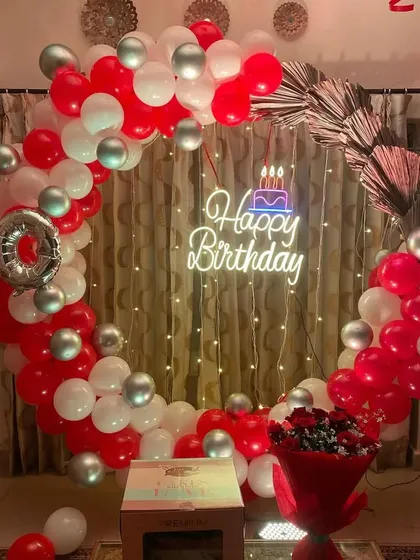 A festive red and white balloon ring for a 40th birthday, with a neon sign and fairy lights in the background.