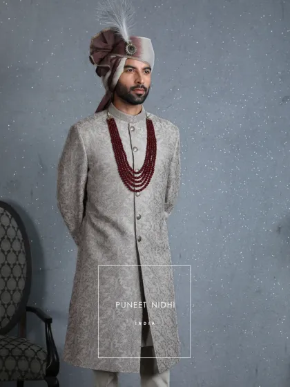 A detailed look at the coffee beige jacquard sherwani, showcasing the subtle floral weave and aariwork. It is a testament to the timeless poise of royal silhouettes.