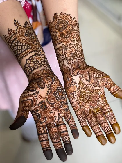 A lush, floral-heavy bridal design. This pattern is filled with roses and leaves, creating a garden on the bride's hands and arms.