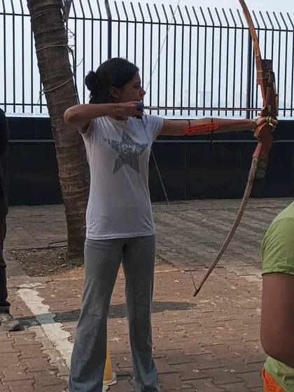 This student demonstrates the proper technique for holding the bow and drawing the string, with an instructor observing nearby.