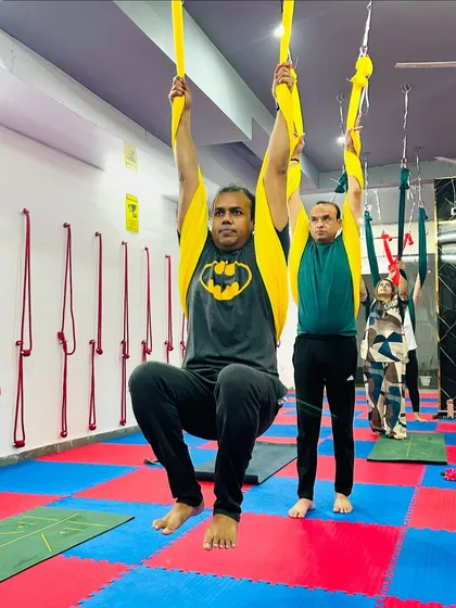 Aerial yoga is not just for the flexible; it's a great way to build strength. Here, students use the hammocks for suspended pull-ups, engaging their core and upper body.