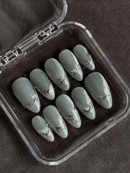 For those who love a modern, edgy vibe. This set features a muted sage green base with raised, liquid-like silver chrome accents. The 3D detailing gives these custom press-on nails a unique texture that looks and feels like wearable art.
