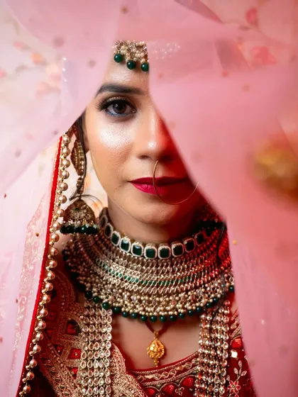 A creative "veil shot" where I capture the bride's face partially obscured by her pink dupatta, creating a sense of mystery and beauty.