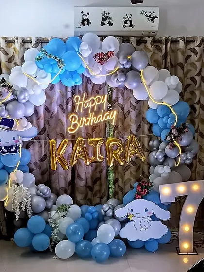 A dreamy Cinnamoroll themed balloon ring for a 7th birthday. The setup uses a lovely blue, white, and grey color palette with character cutouts and a light-up marquee number.