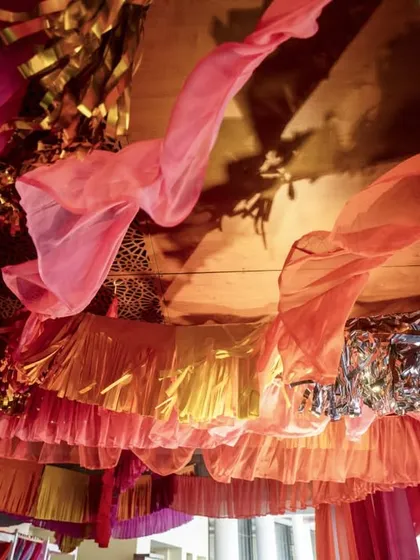 A view from below the canopy, showing the rich layers of different fabrics and textures, including sheer drapes and metallic tassels.