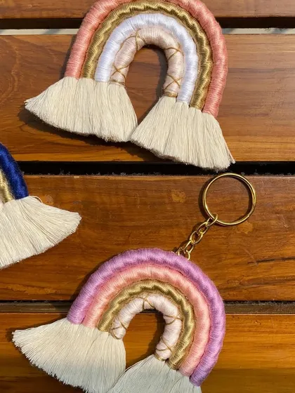 A closer look at our macrame rainbow keychains in different color palettes. Here you can see a pink and gold version alongside the blue and gold one, showing some of the custom options available.