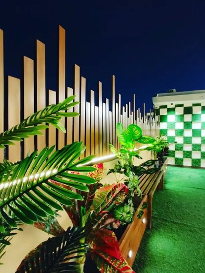 A close-up of the lighting and plants against the unique checkered wall and slatted privacy screen.