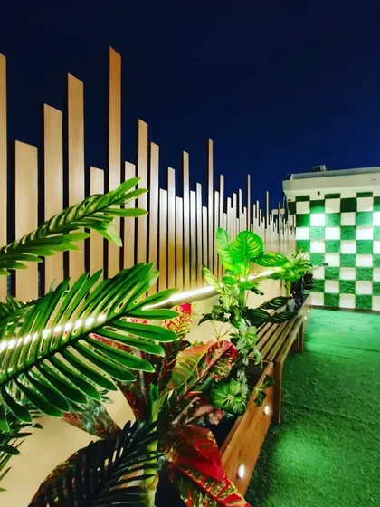 A close-up of the lighting and plants against the unique checkered wall and slatted privacy screen.