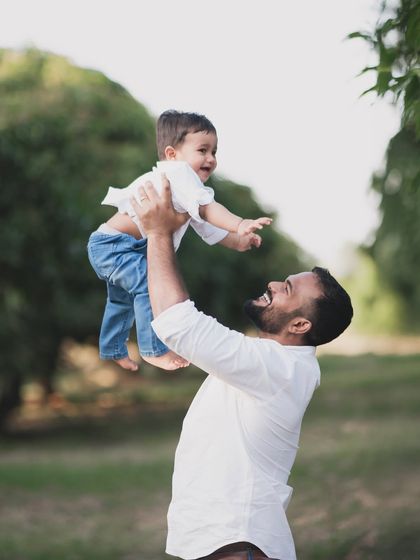 A father joyfully lifting his son into the air during an outdoor family photoshoot.