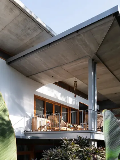 The powerful form of a cantilevered roof provides shade to the upper balcony, showcasing a key element of tropical modernist architecture.