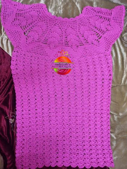 This bright pink top was made exactly as the customer wanted. It features a lovely fan-stitch pattern around the neckline and a shell-stitch body, creating a beautiful, textured garment.