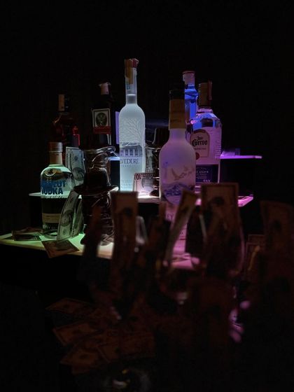 A moody shot of the bar setup, highlighting the premium spirits available for the event. The dark lighting and themed props create an intriguing and exclusive feel for the party.