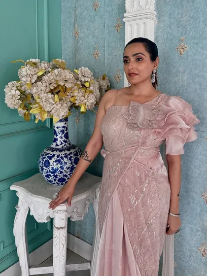 A close-up of the ruffled shoulder detail on this pink draped saree. It's a fashionable and unique design element.