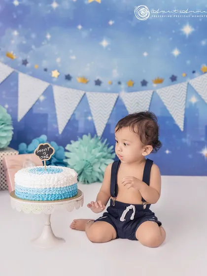 The moment before the smash! This little one is eyeing his first birthday cake, ready for a sweet celebration under a starry blue backdrop.