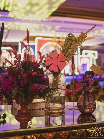 A beautiful tablescape with colorful florals, modern candle holders, and playful cutouts, all contributing to the vibrant sangeet atmosphere.