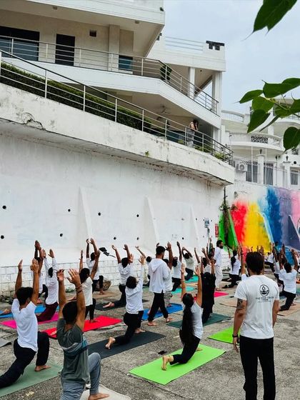 A beautiful shot of our outdoor class practicing Virabhadrasana I (Warrior I) against a colorful mural. Yoga is an art, and we love practicing in inspiring locations.