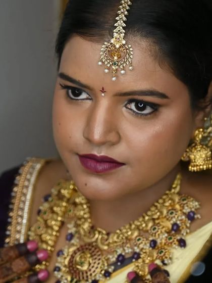 A close-up of bridal elegance. This mirror shot of my bride Sugandhi captures her flawless makeup, bold lip color, and the intricate details of her temple jewellery.