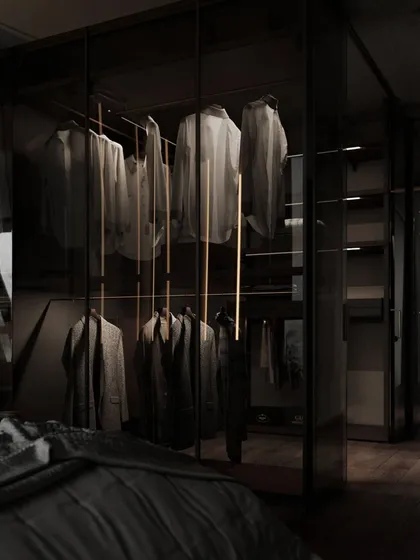 This is the kind of walk-in closet we love to design: dark, moody, and exceptionally functional. Smoked glass doors provide a glimpse of the organized space within, where integrated LED lighting highlights the clothing. The design creates a sophisticated, boutique-like experience right inside the home.