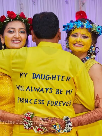 A heartwarming photo of the bride and her sister hugging their father, whose shirt reads "My Daughter Will Always Be My Princess Forever." I capture these emotional family moments that tell a deeper story.