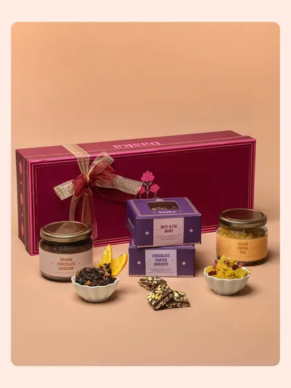 A product group shot for a Rakhi hamper, showcasing jars of dry fruits and boxes of sweets. The arrangement is designed to show the variety and value within the festive collection.