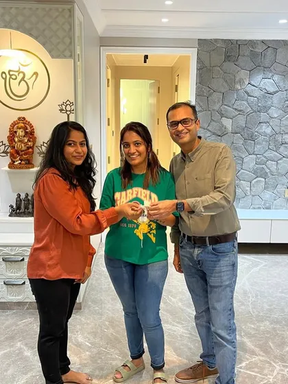 Handing over the keys to this beautiful home. In the background, you can see the finished stone texture TV wall and the elegant pooja unit we designed, all ready for the clients to enjoy.