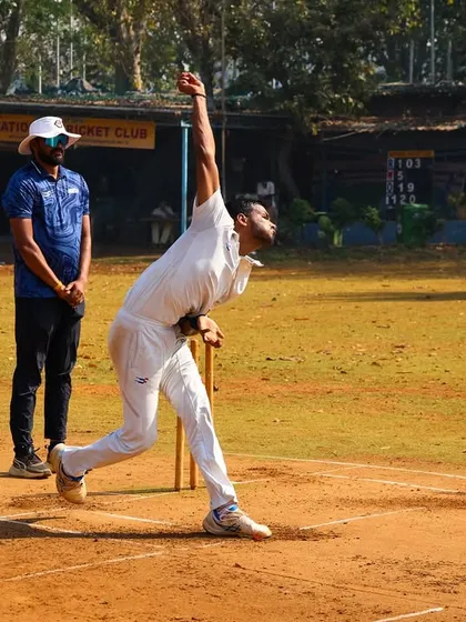 A fast bowler hitting his stride under the watchful eye of our coach during a practice game.
