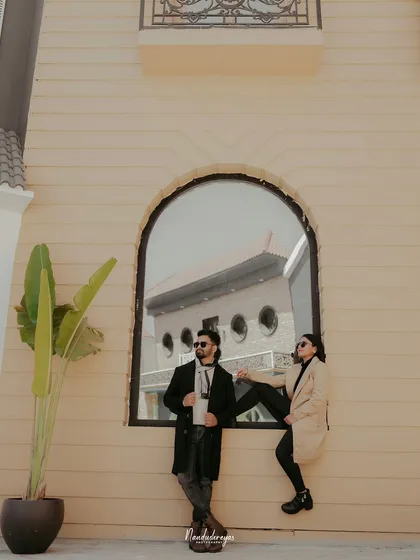A creative and fashionable pose with a couple using a large arched window as a frame.
