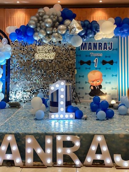 A Boss Baby themed first birthday with a shimmer wall. This stage setup combines a popular character theme with a glamorous silver sequin backdrop and large marquee letters.