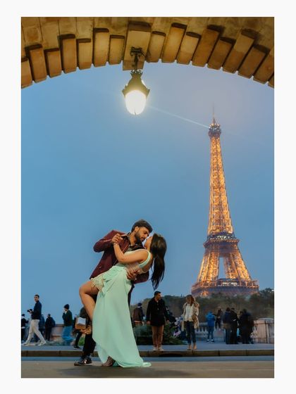A grand, romantic dip and kiss on a bridge in Paris, with the illuminated Eiffel Tower in the background. This is an iconic, must-have shot that captures the magical essence of a Parisian pre-wedding shoot.