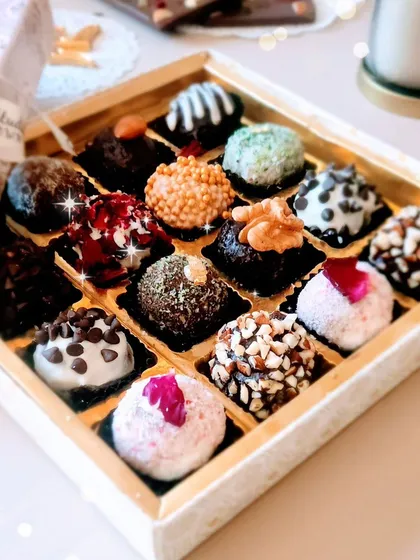 A box of our assorted crunchy chocolate truffles, ready for a bulk order. Each truffle is uniquely flavored and textured, with toppings like chopped nuts, chocolate chips, and sprinkles.