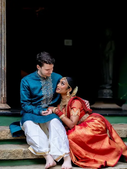 A cross-cultural couple shares a quiet moment on the steps, their different attires blending beautifully in the heritage setting.