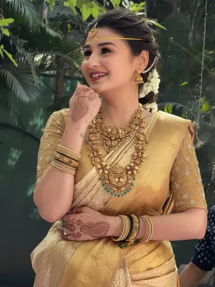 A candid shot of the South Indian bride, her face lit up with a smile. Her traditional attire and glowing makeup make her look like a queen.