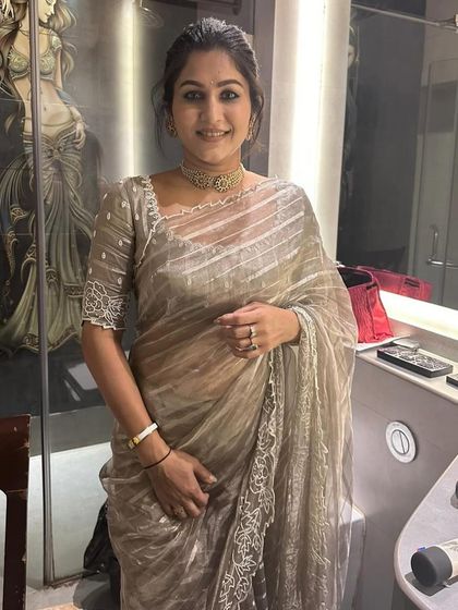 A smiling portrait of Sahana. The custom blouse with its intricate beadwork and square neckline perfectly complements her delicate jewelry.