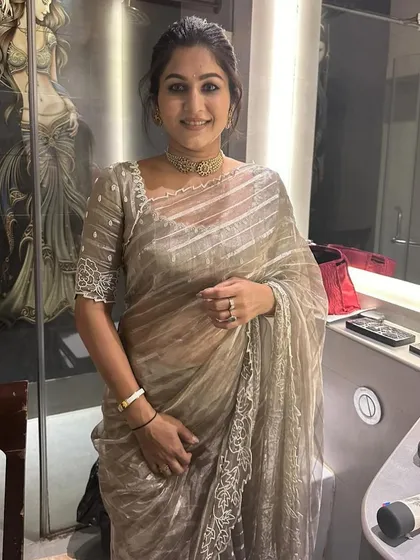 A smiling portrait of Sahana. The custom blouse with its intricate beadwork and square neckline perfectly complements her delicate jewelry.