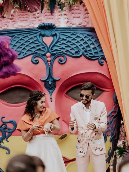 The couple on stage, enjoying the festivities of their vibrant carnival-themed wedding event.