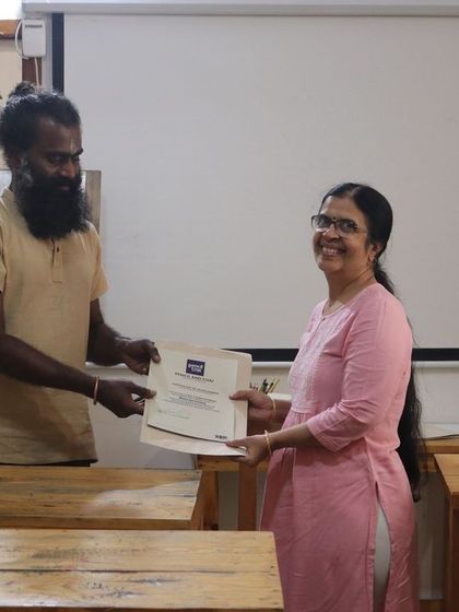 A smiling student proudly holds her certificate. Her hard work and dedication have paid off, and we are thrilled to be a part of her artistic journey.